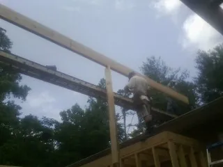 Carpenter setting a ridge beam over a new addition frame — Ice Dam Removal by Roofing Brothers in Port Jefferson