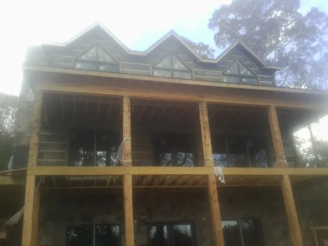 Dormers and porch framing on a large log home under construction — Roof Coating work by our crew in Port Jefferson