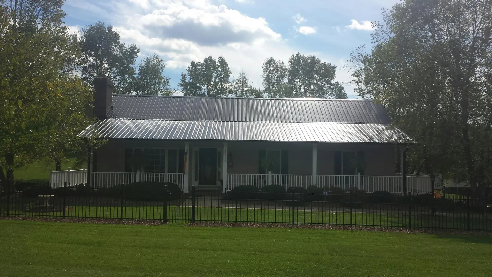 Gray metal roof on a brick ranch with a full width front porch — Gutter Guard Installation work by our crew in Port Jefferson