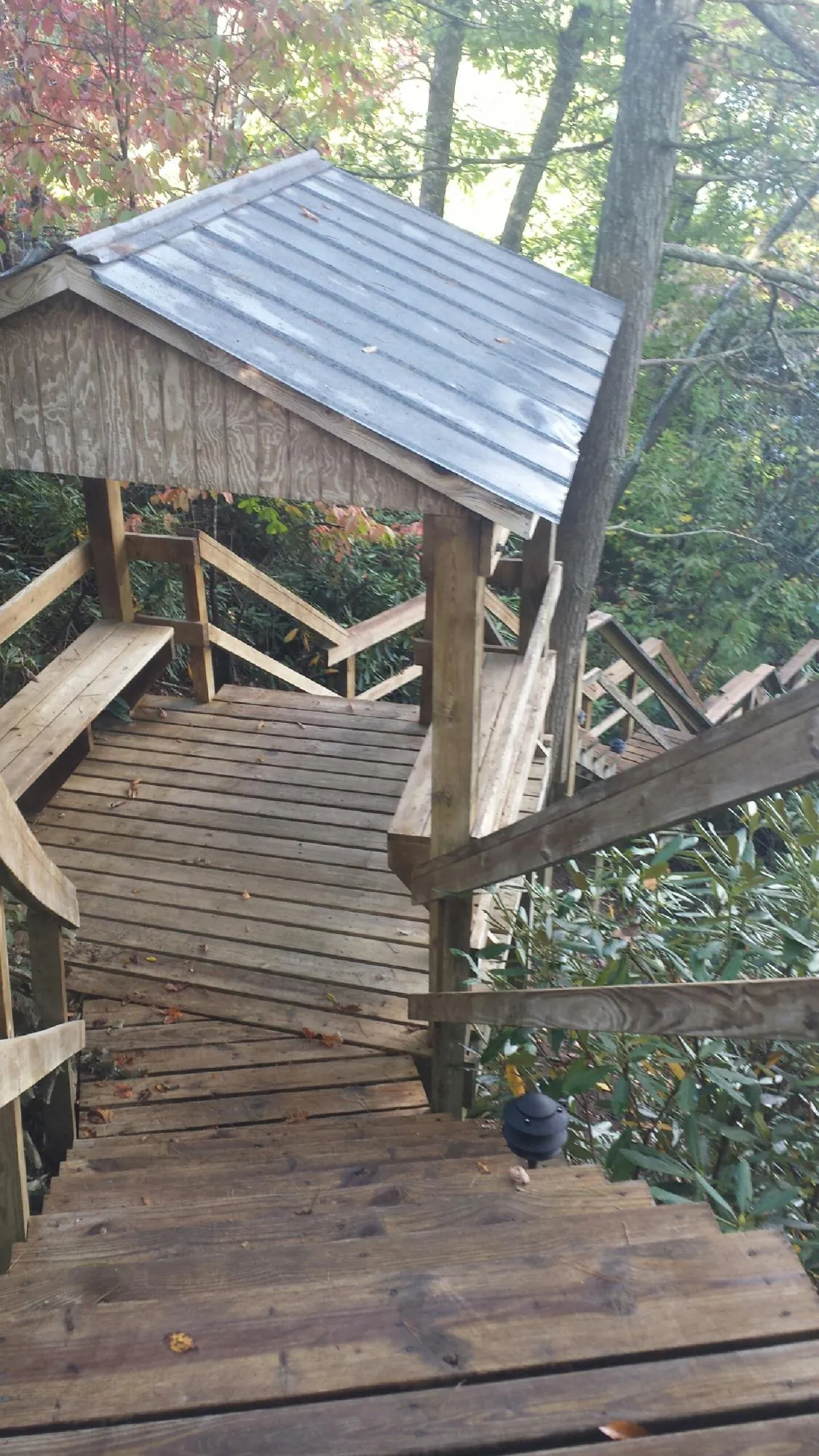 Metal roofed shelter over wooden steps on a wooded walkway — Skylight Repair & Installation work by our crew in Port Jefferson