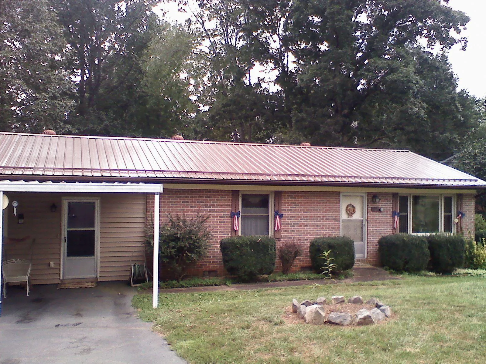 Bronze metal roof and carport on a brick ranch home — Roof Repair work by our crew in Port Jefferson