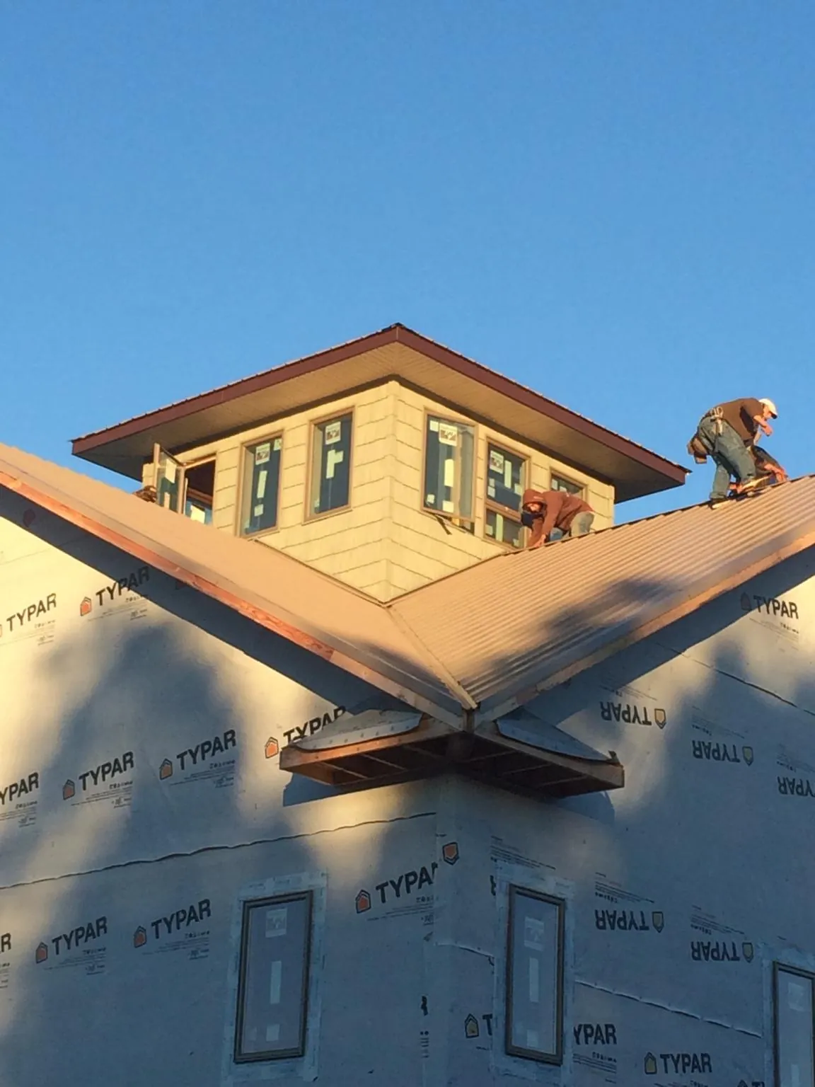 Roofers working around a rooftop cupola on a new metal roof at sunset — Roof Waterproofing in Port Jefferson by Roofing Brothers